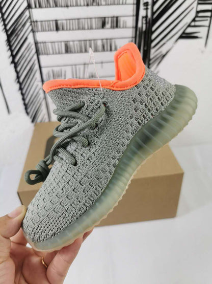 Angled side view showing the gray knit-style upper, lacing system, orange collar, and ribbed sole.