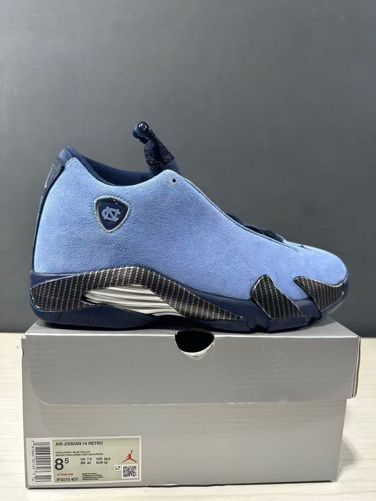 Close side view of the blue Jordan Air Jordan 14 sneaker and its box label showing EU 42, US 8.5, UK 7.5, and CM 26.5.