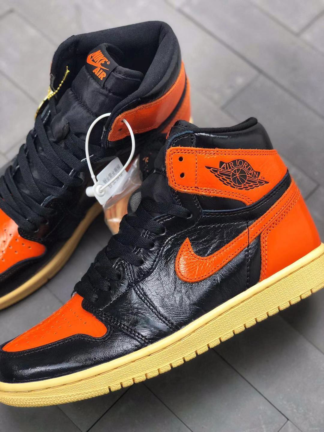 Detailed three-quarter view showing the orange collar, Air Jordan wing branding, black laces, and textured black upper.
