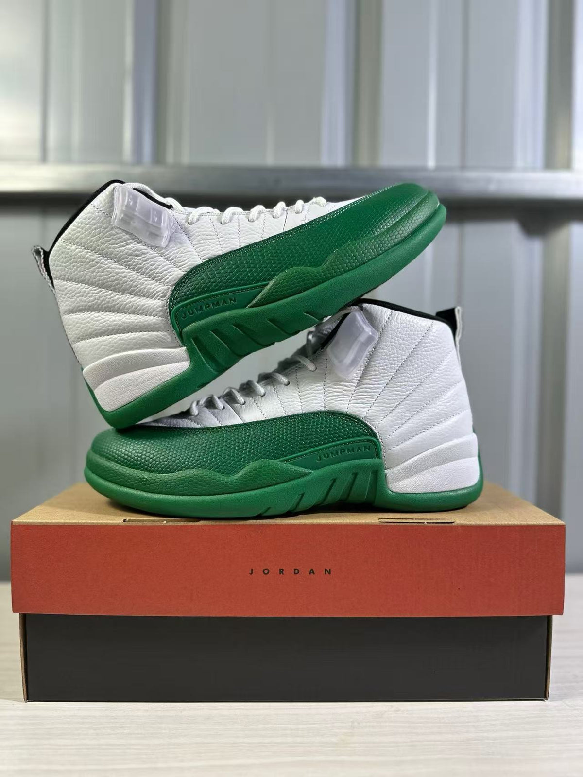 Pair of white and green Jordan high-top sneakers posed on a Jordan shoebox.