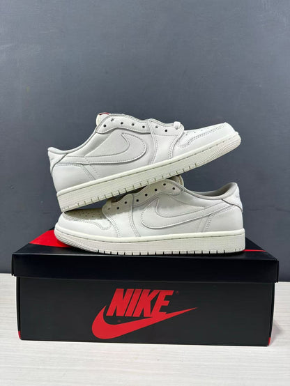 Two white low-top Jordan sneakers stacked on a shoe box, showing the side panels, perforated toe boxes, and rubber outsoles.