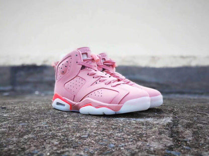 Front three-quarter view of a pair of pink Air Jordan 6 high-top sneakers with red and white outsole accents.