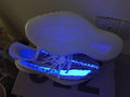 Side and outsole view under blue light, showing the illuminated upper and translucent sole.