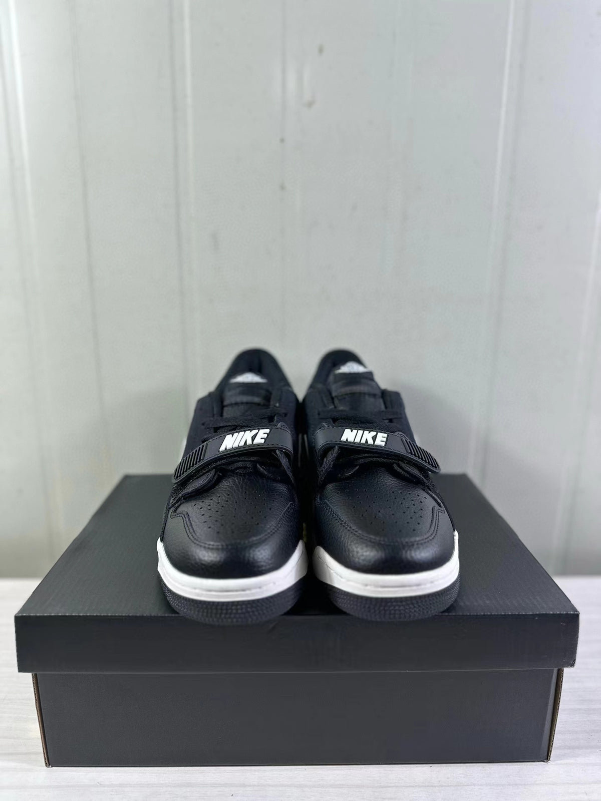 Front view of the sneakers showing perforated black toe boxes, black straps, and white midsoles.