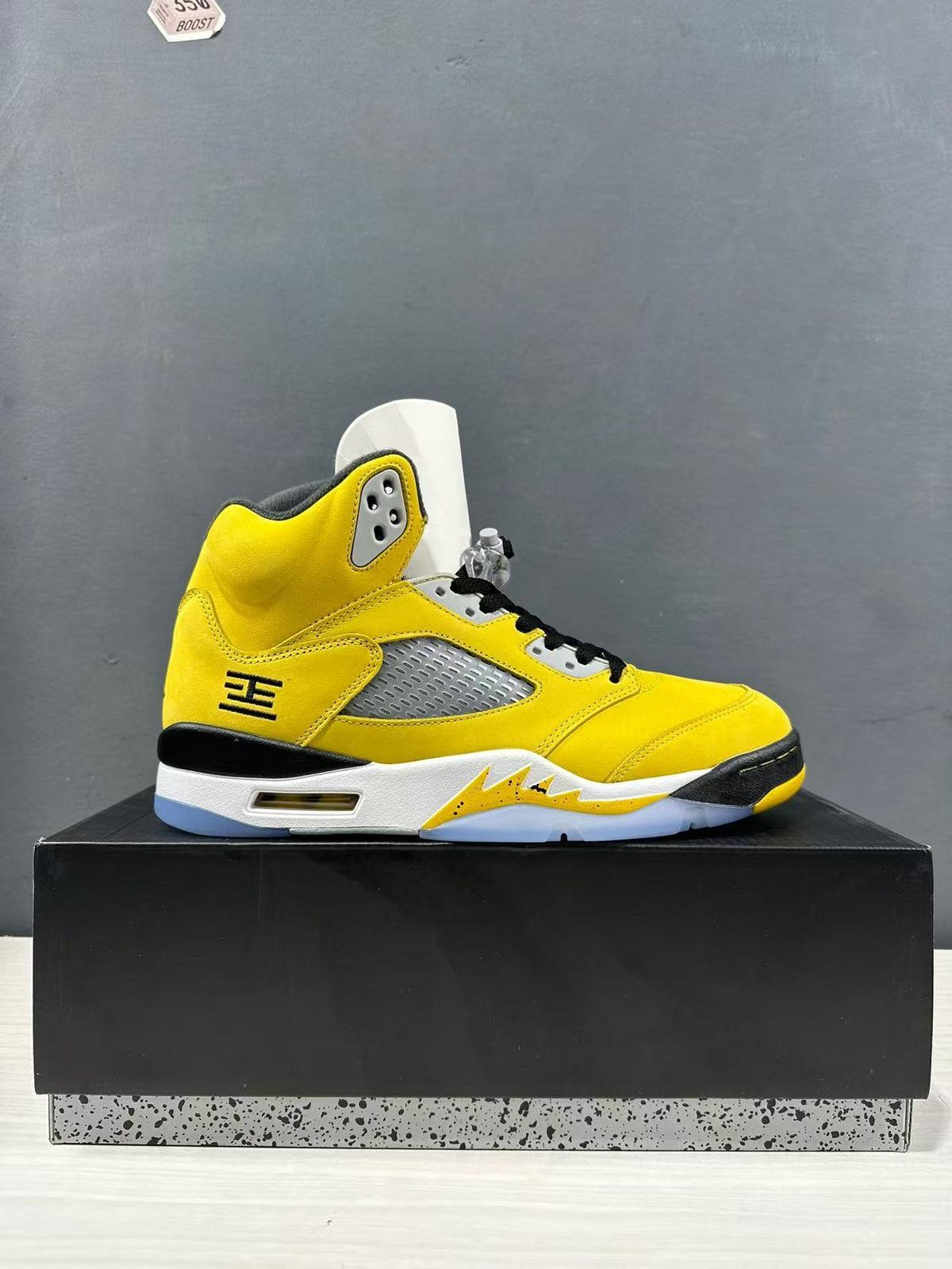 Single yellow sneaker shown in side profile with gray mesh panel and translucent outsole.