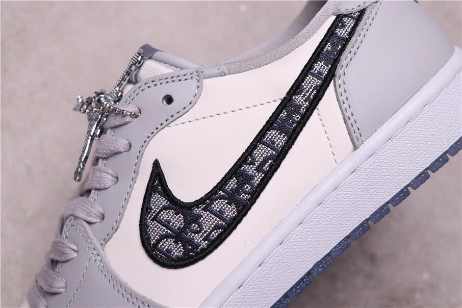 Side close-up showing the patterned black Swoosh, grey overlays and metallic lace accessory.