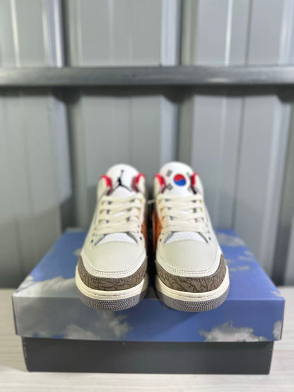 Front view of the pair showing cream laces, white toe boxes, brown overlays, and blue-red tongue details.