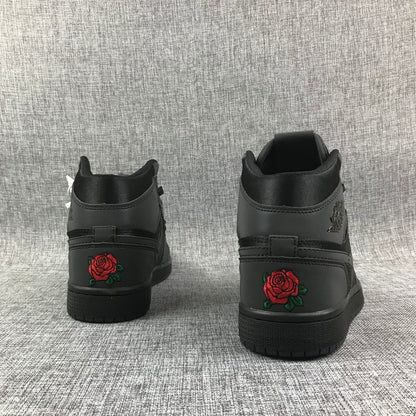 Rear view of the black high-top sneakers showing red rose embroidery with green leaves on the heels.