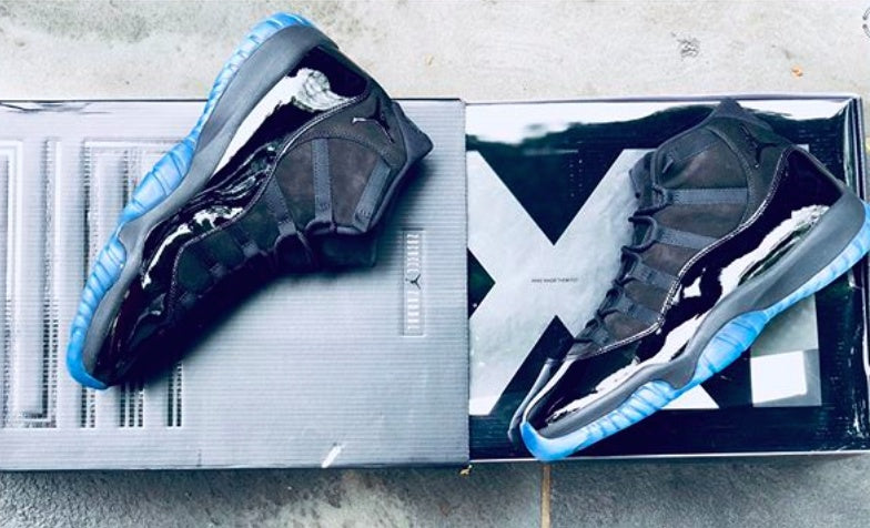 Black sneakers arranged on presentation boxes, showing the side panels and translucent soles.