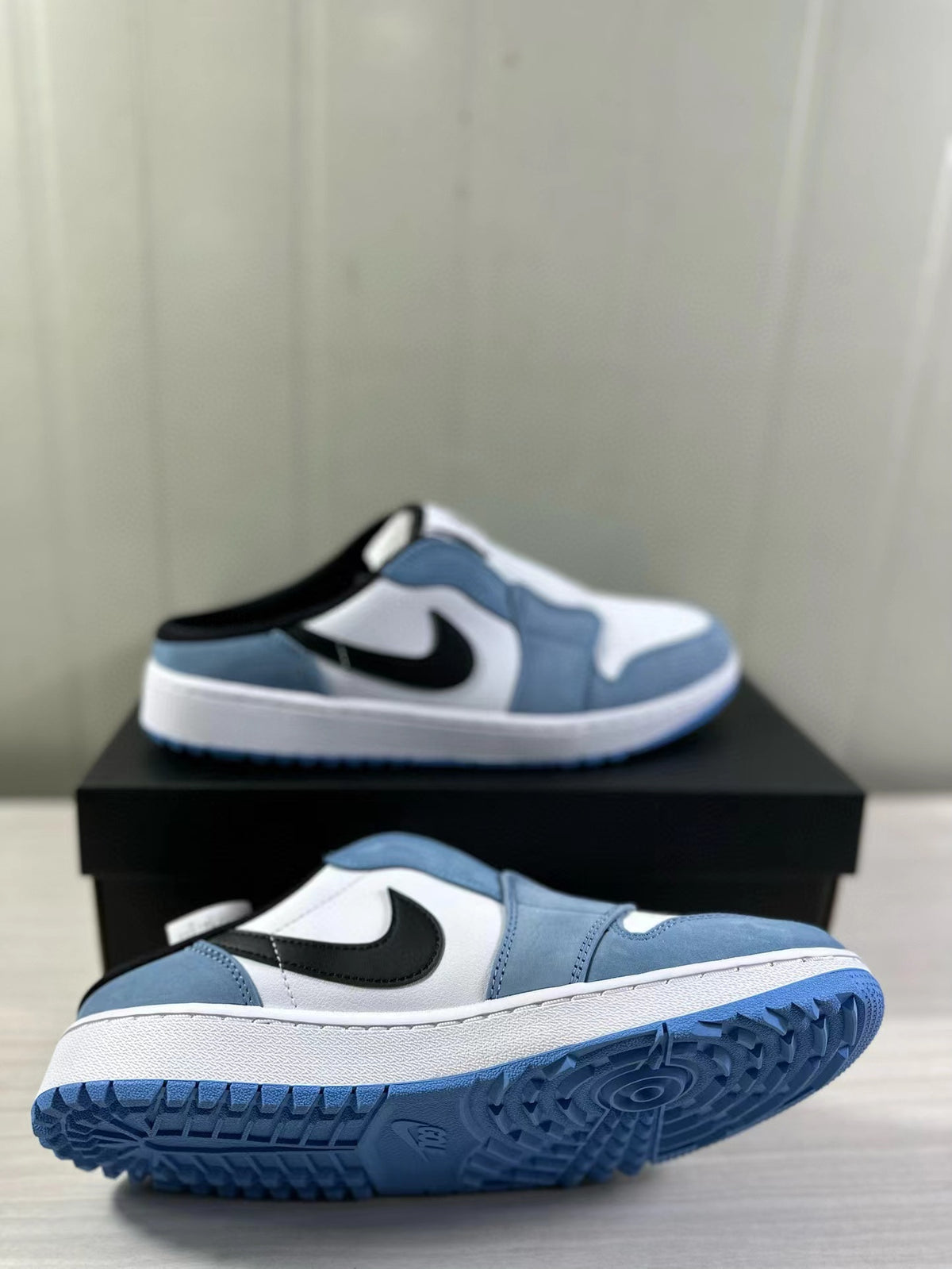 Angled view showing the open heel, black side logo, white midsole, and blue outsole.