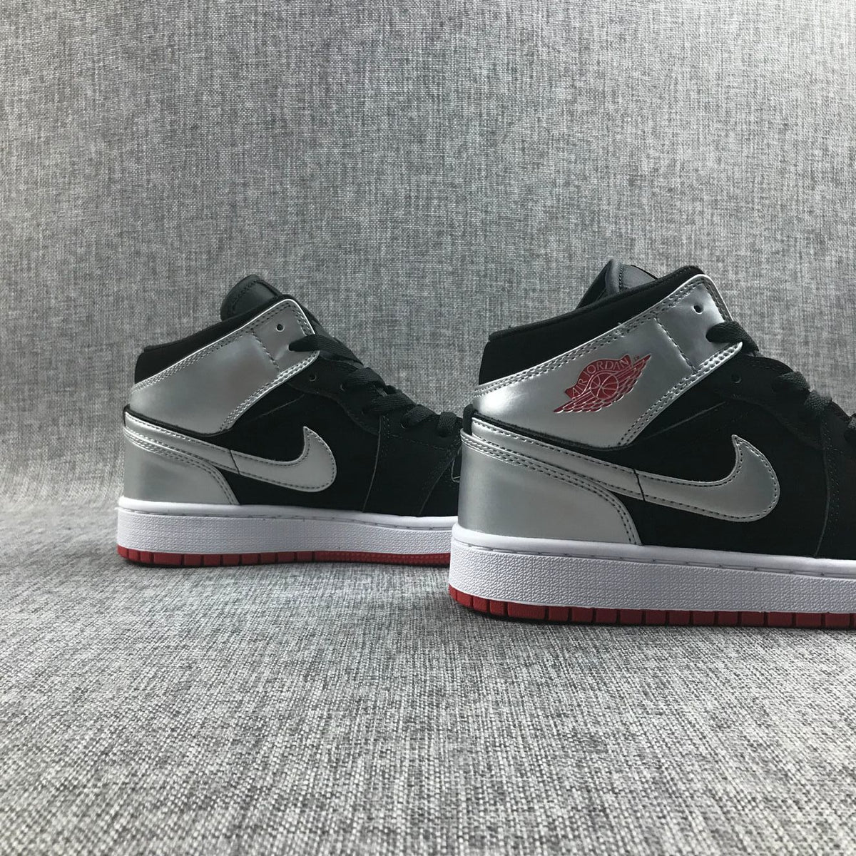 Pair of black and silver mid-top sneakers shown from the side.