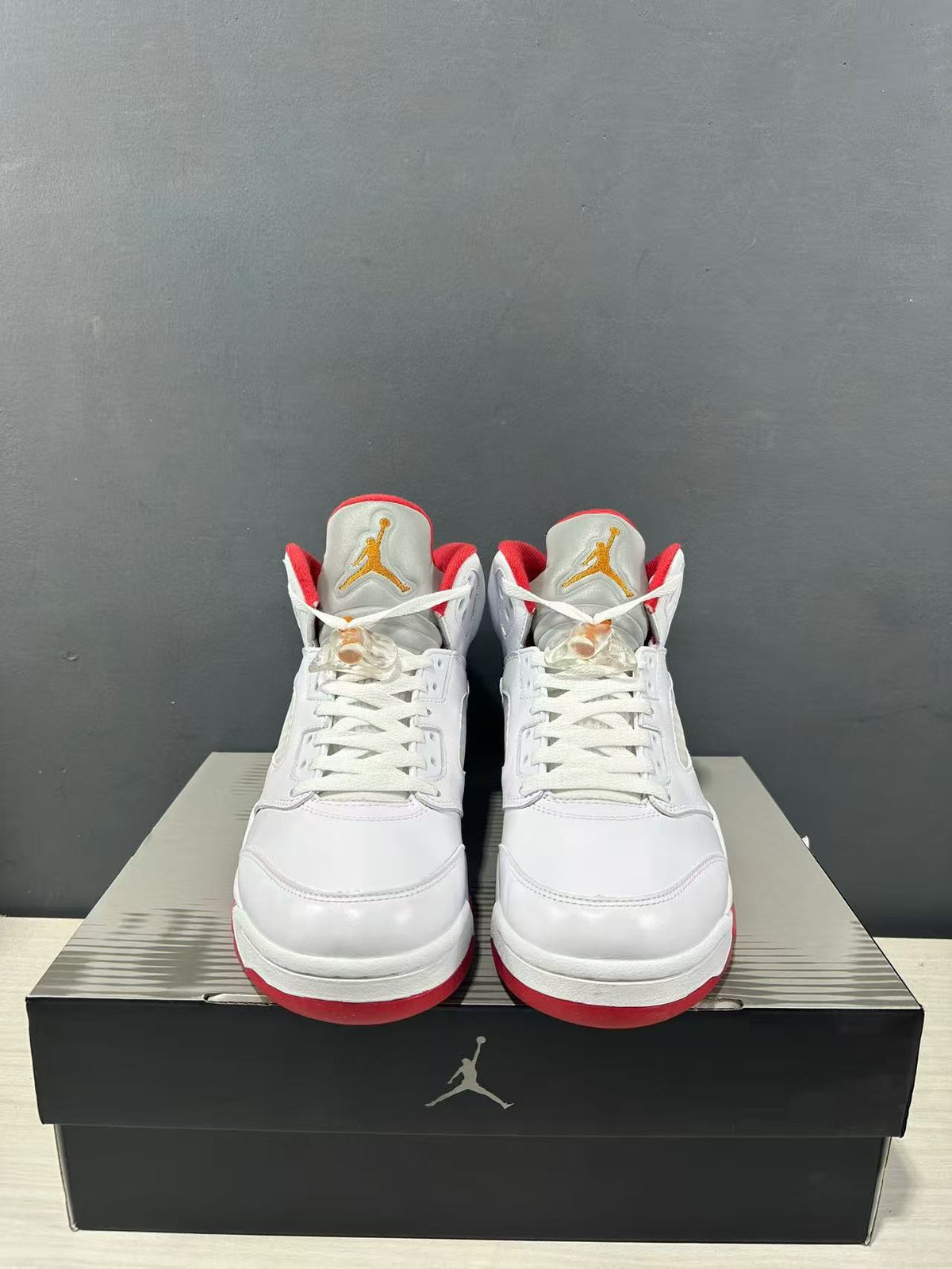 Front view of the pair showing white uppers, red lining and gold-colored tongue logos.