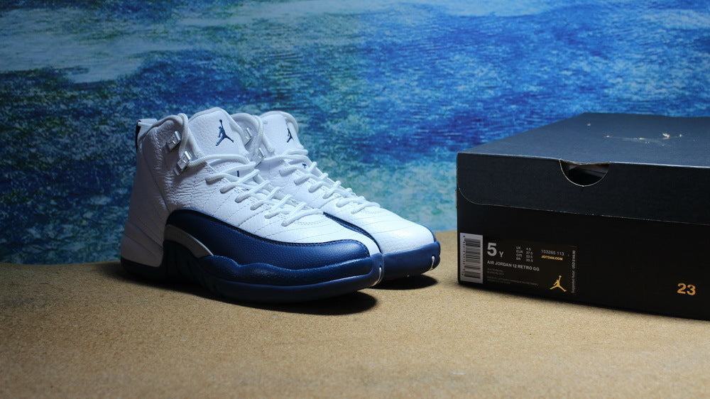 White and navy Jordan high-top sneakers displayed beside a black shoe box.