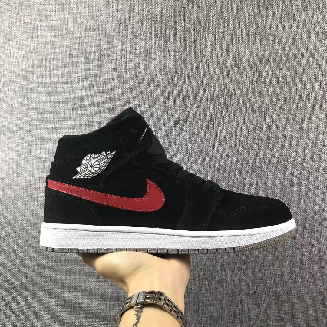Side view of a black Jordan 1 Mid sneaker with a red Swoosh, white midsole, and gray outsole.