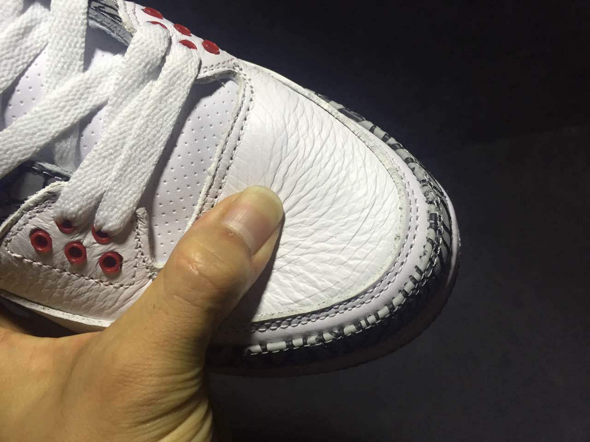 Close-up of the white textured toe area, perforations, stitching, and red eyelet details.