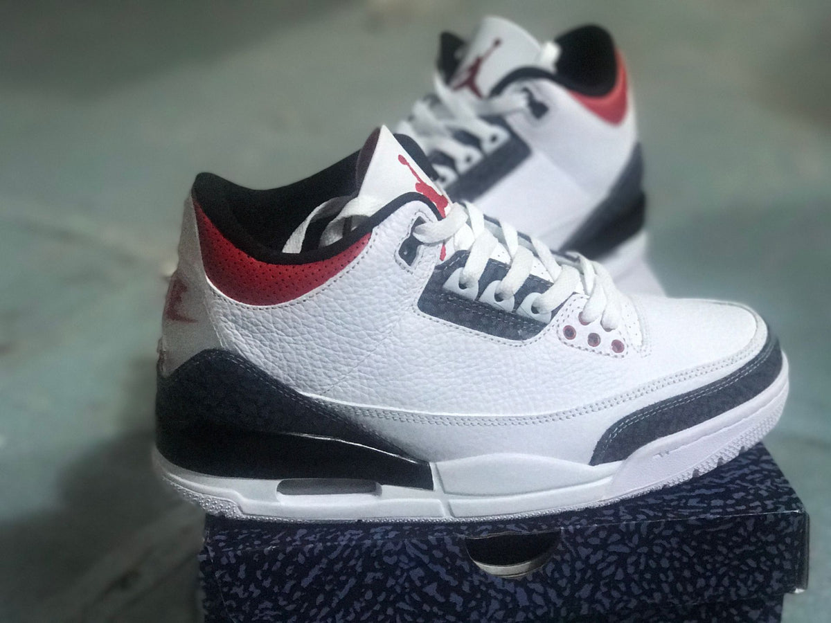 Side view of a white Jordan 3 Retro SE with black patterned overlays and red collar accents
