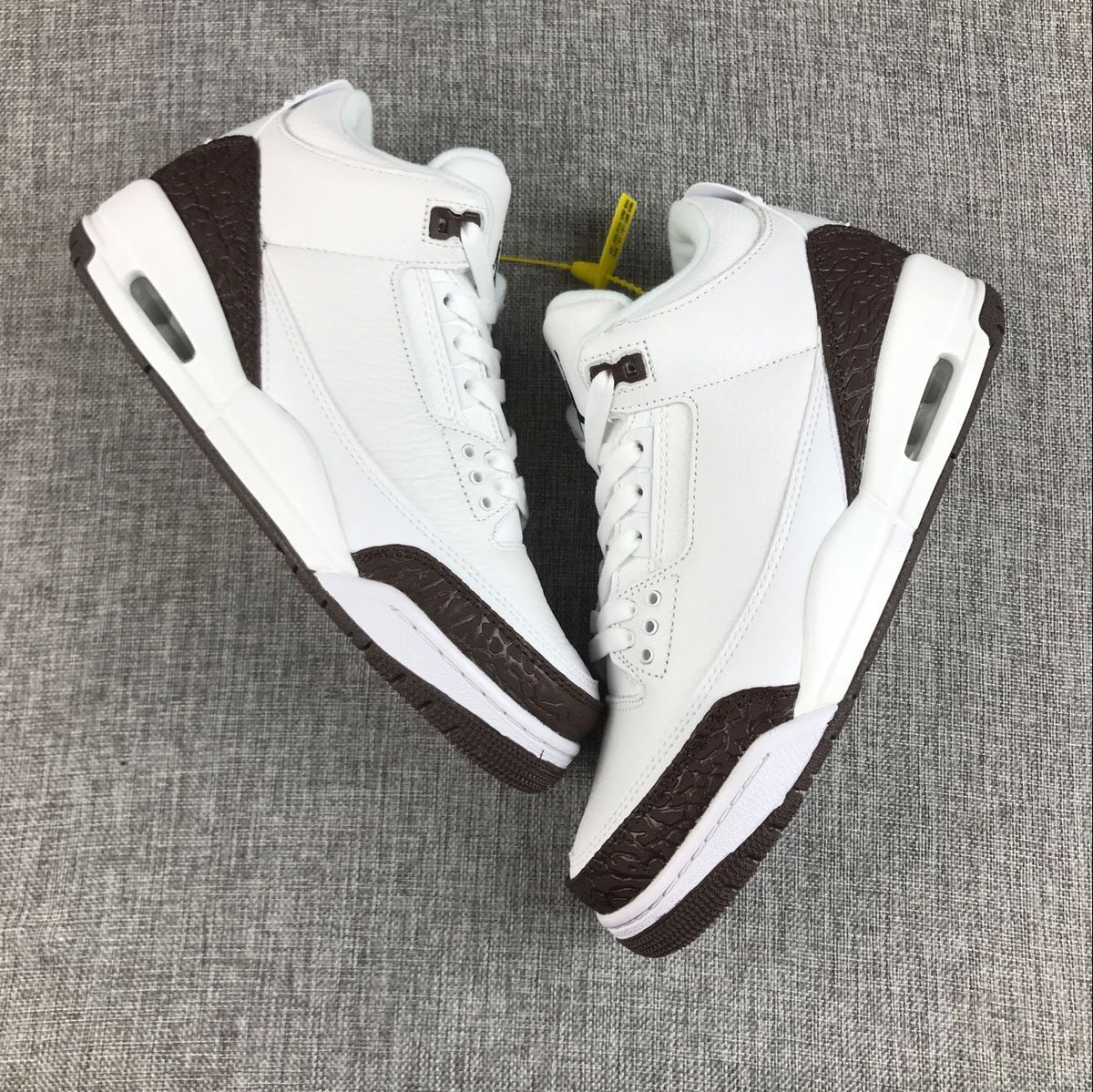 Top-down view of a pair of white and brown Jordan Air Jordan 3 sneakers.