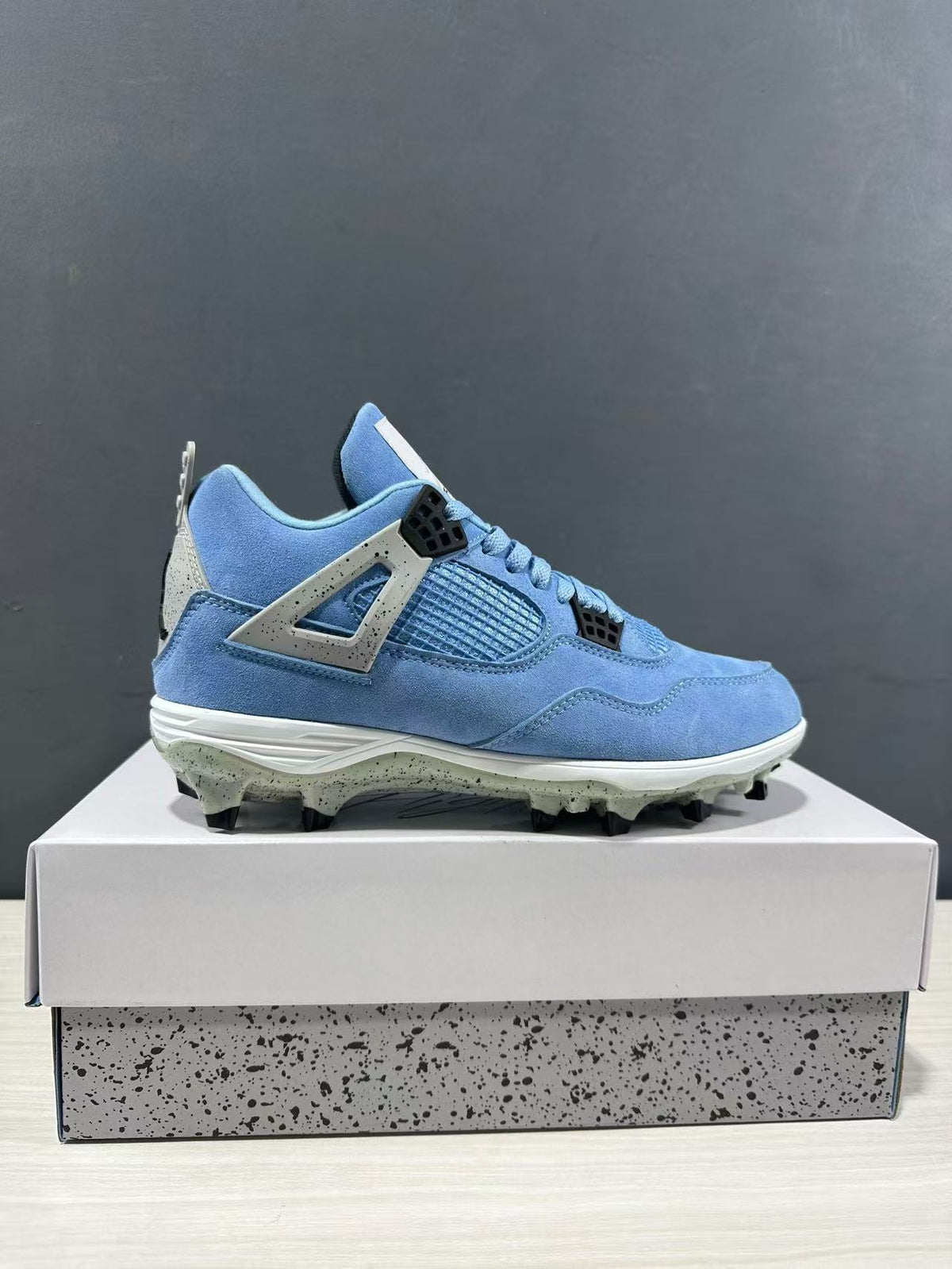 Side profile of a University Blue Jordan Air Jordan 4 sneaker displayed on a shoebox.