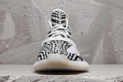 Front view of the sneaker showing the patterned knit toe box, white laces, and light-colored outsole.