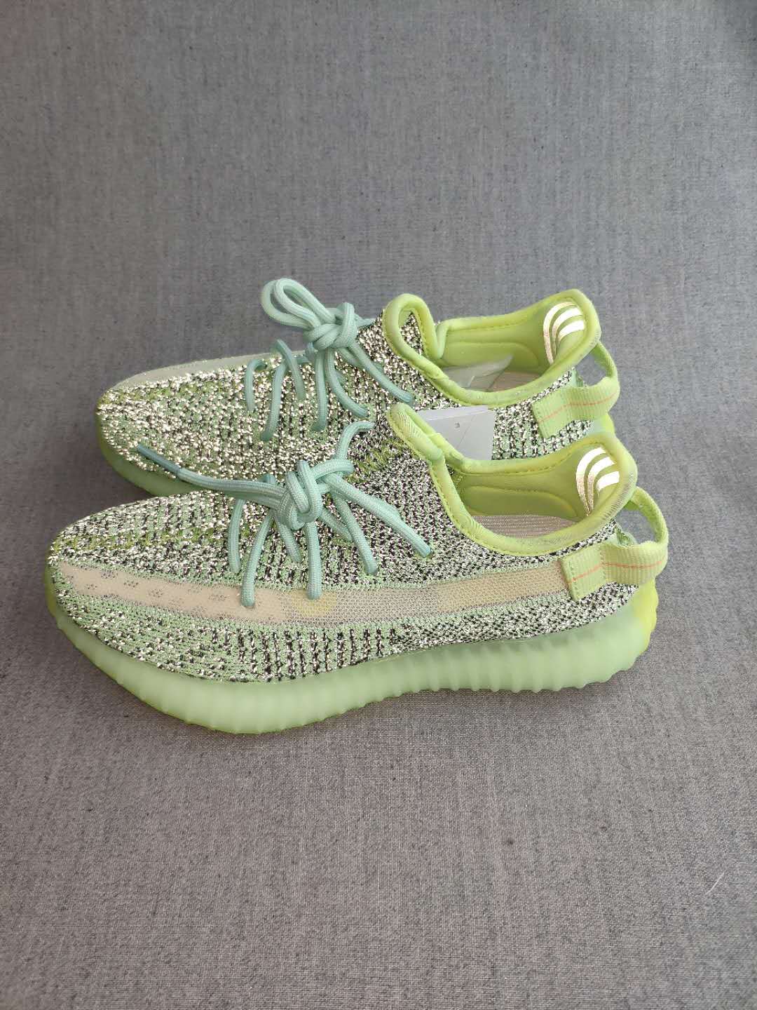 Pair of green and black patterned Yeezy 350 V2 sneakers shown from above on a gray background.
