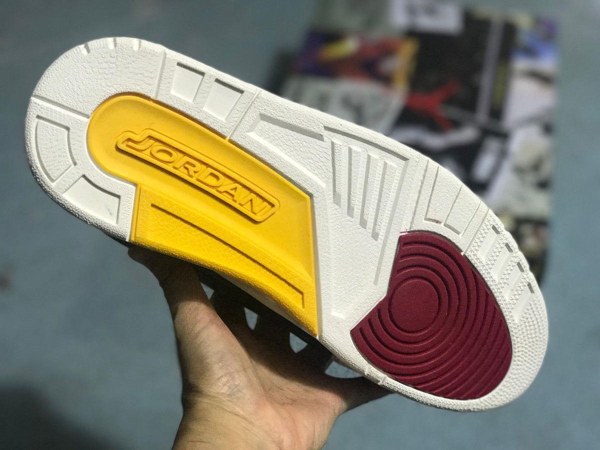 Outsole view showing a light-colored tread with yellow and burgundy sections.
