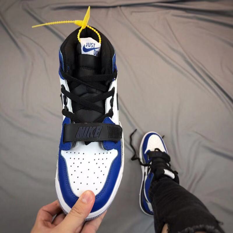 Top-down view of the sneaker showing black laces, a black strap, perforated toe box, and blue trim.
