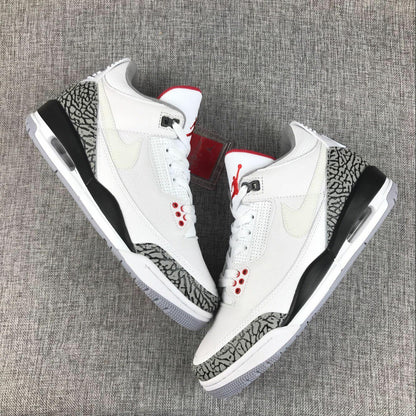 Top-down view of a pair of white Jordan sneakers with grey elephant-print overlays and red tongue accents.