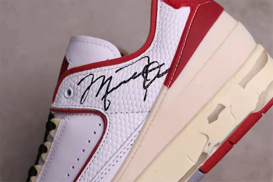 Close-up of the white textured side panel, red trim, printed graphic, and cream midsole.