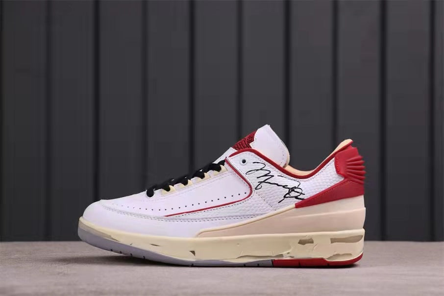 Side profile highlighting the white upper, red heel and collar accents, black graphic detail, and cream midsole.