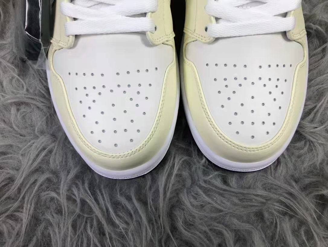Close-up of the perforated white toe boxes framed by cream-colored overlays.
