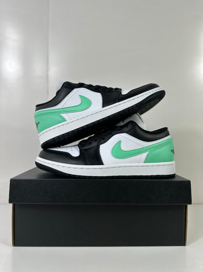 Pair of white, green, and black low-top sneakers arranged on a black shoebox.