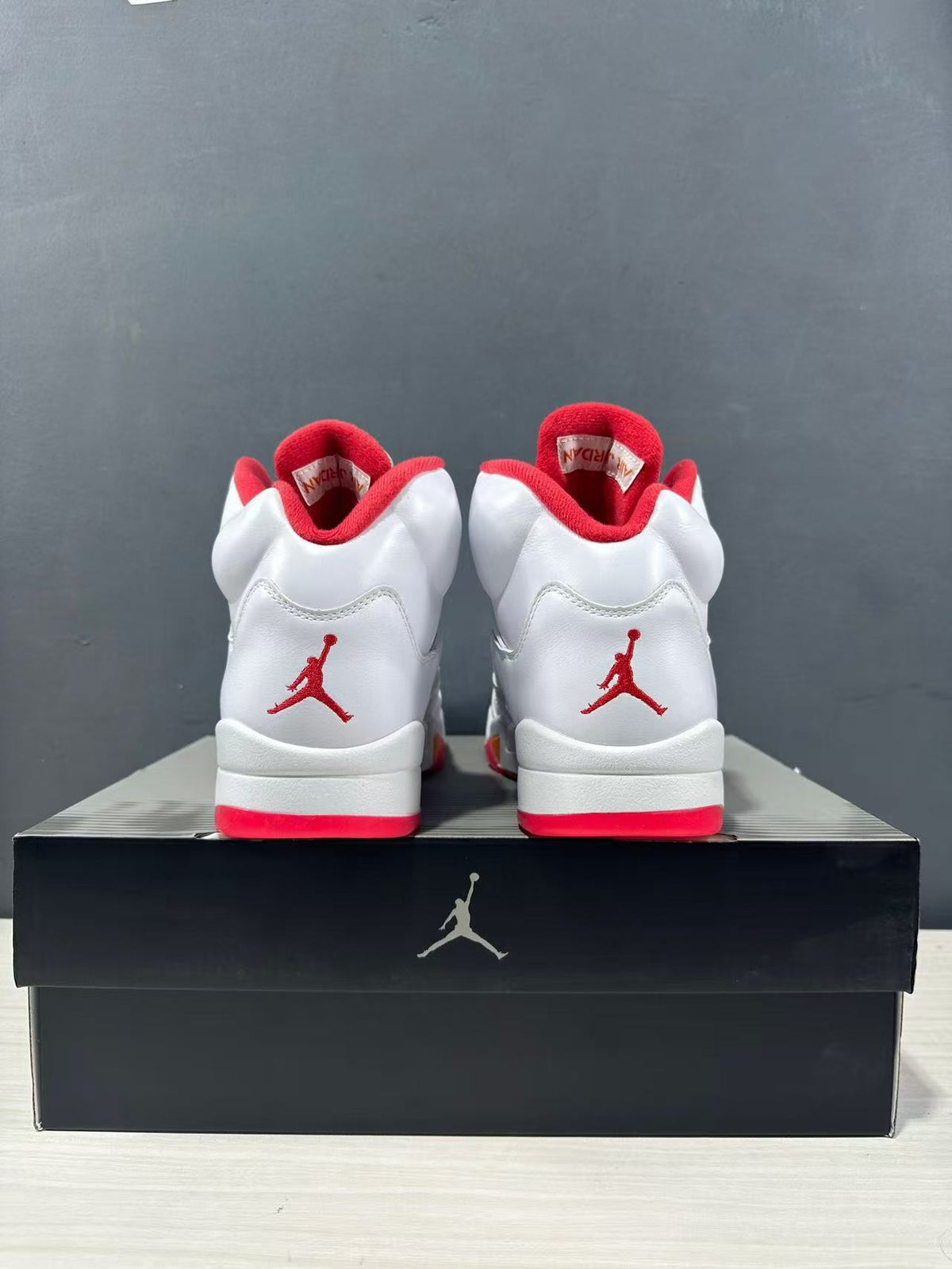 Rear view of the pair showing red heel logos, white uppers and red outsole sections.
