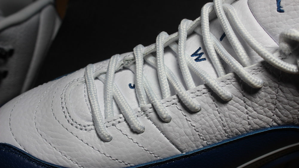 Close-up of white laces, stitched white panels, and navy trim.