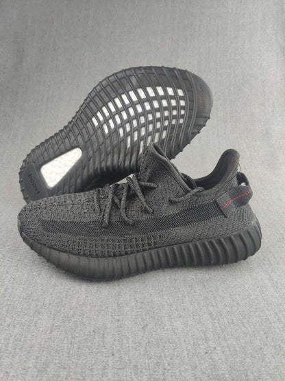 Pair of black knit low-top sneakers shown from the side and outsole.