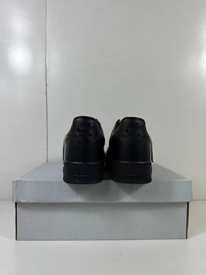 Rear view of a pair of black low-top sneakers with black heel panels and embossed branding.