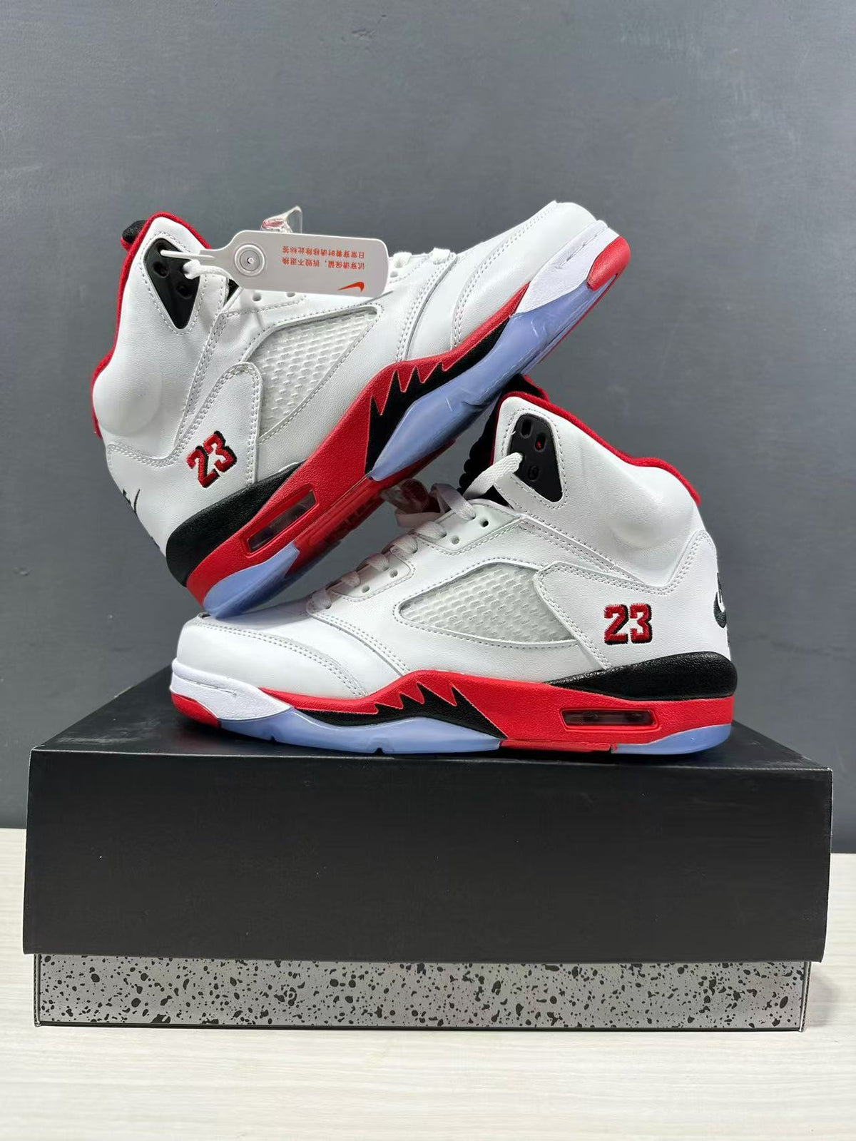 Pair of white and red high-top sneakers arranged on a box, showing mesh side panels, black midsole sections, and translucent outsole areas.