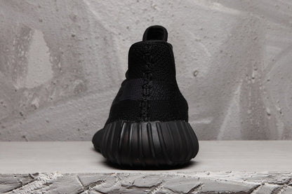 Rear view of a black Yeezy 350 V2 sneaker showing the rounded heel and ribbed sole.