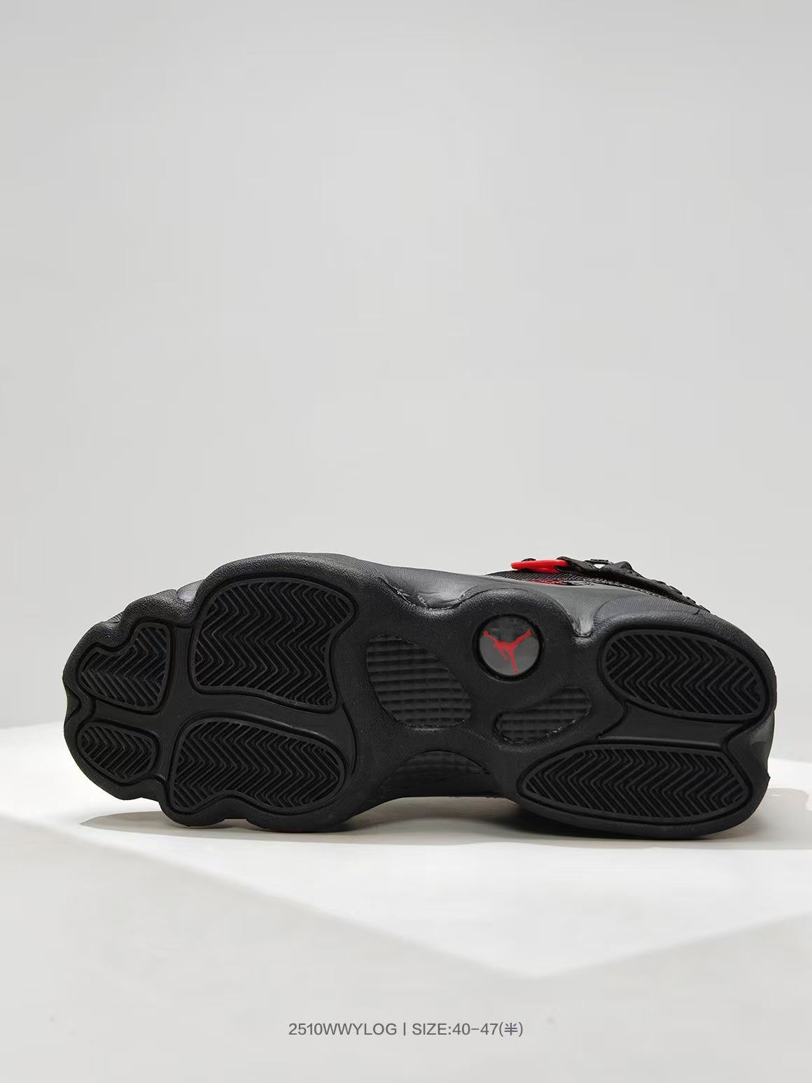 Black sneaker outsole showing a segmented tread pattern and red Jordan emblem.