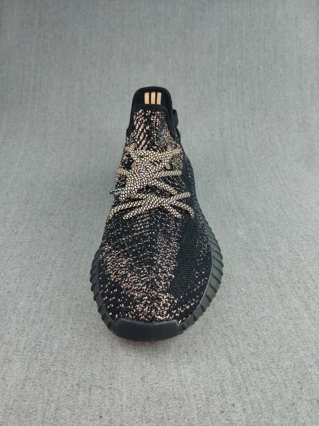 Top view of a black lace-up sneaker showing the patterned upper and rounded toe.