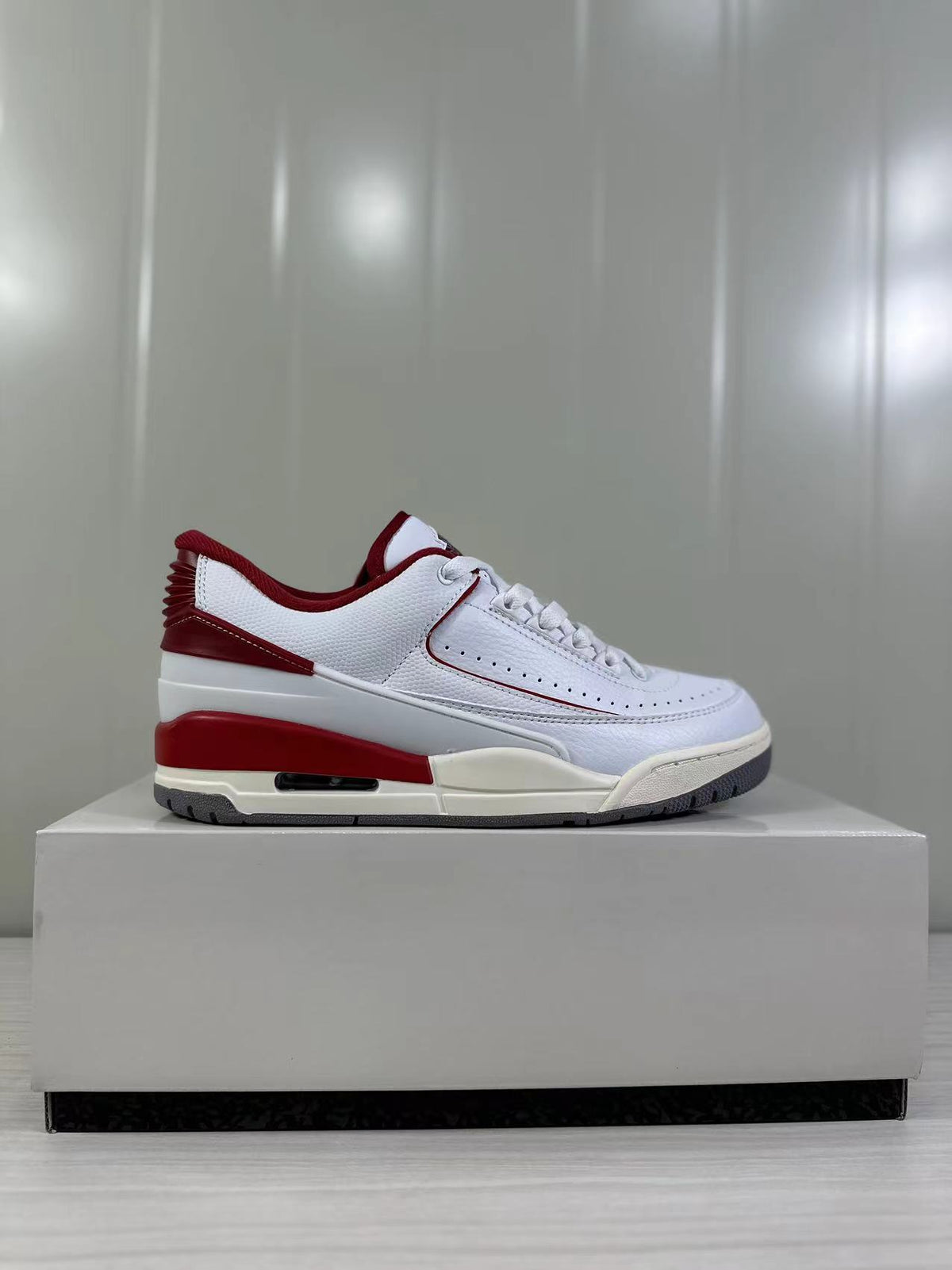 Clean side profile of the white and red low-top sneaker on a display box.