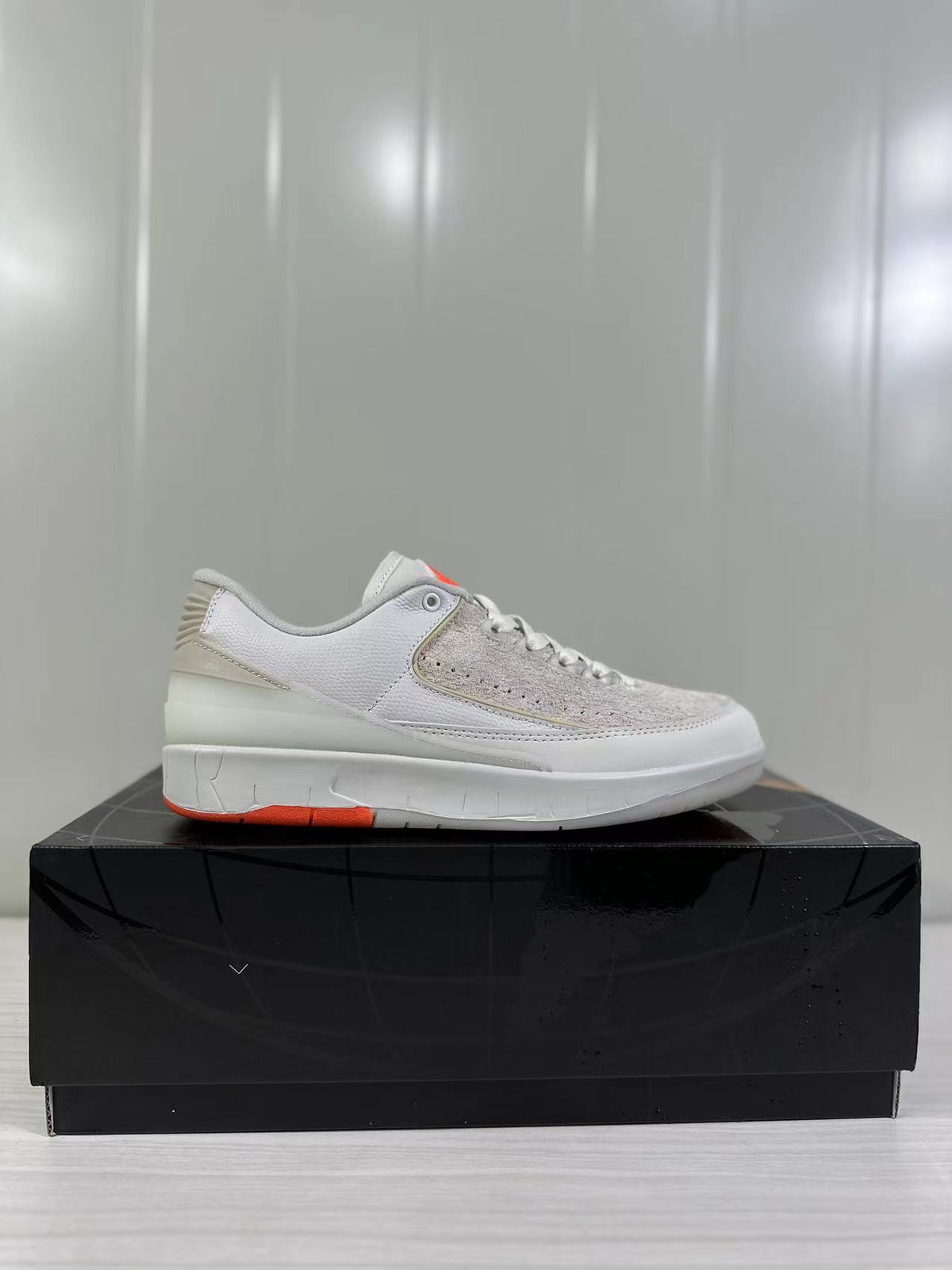 Single side profile of the light beige and white low-top sneaker on a black box.
