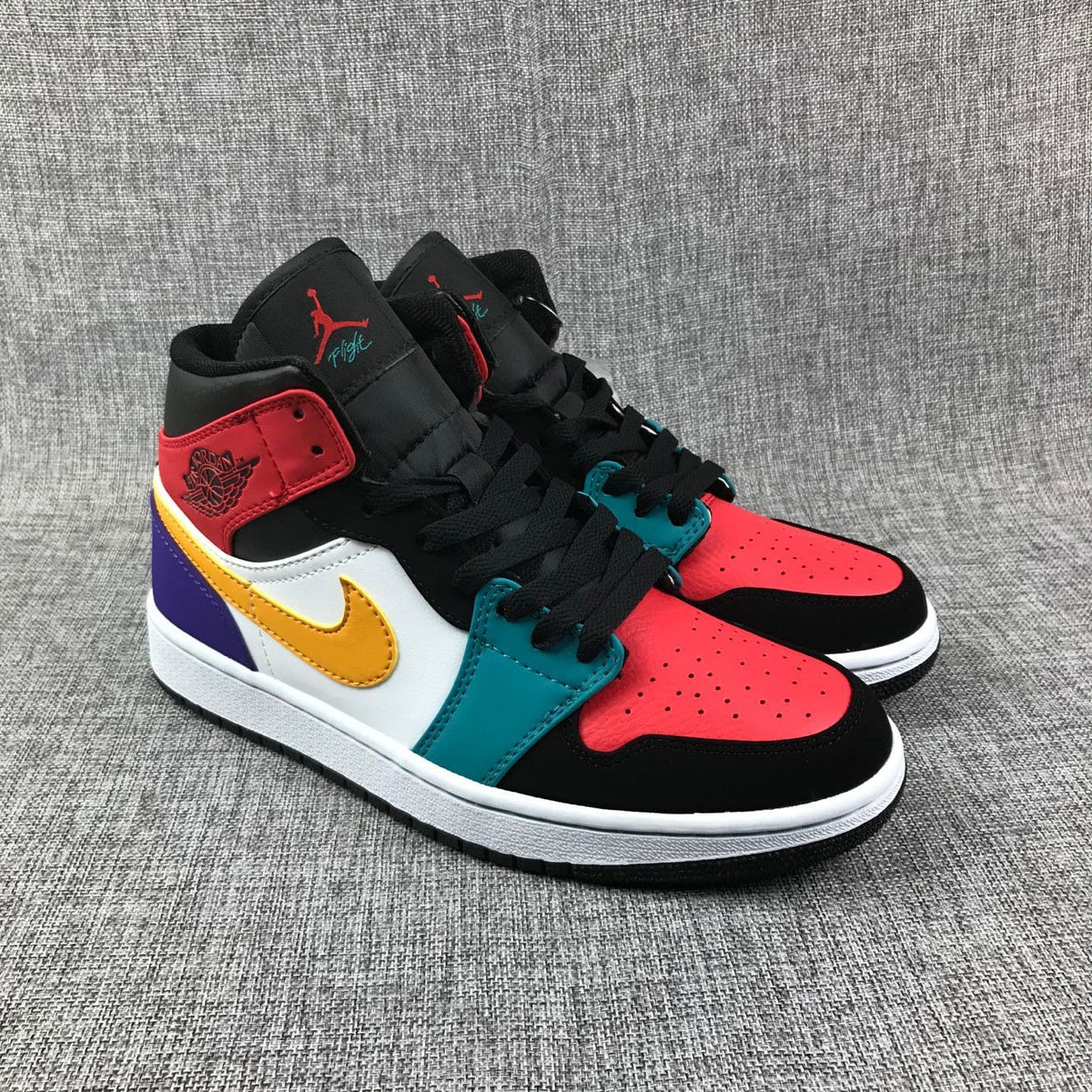 Three-quarter view showing the red perforated toe panels, black overlays and teal eyelet panels.