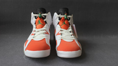 Front view of the pair showing orange toe boxes, white laces, orange tongues, and green Jumpman logos.