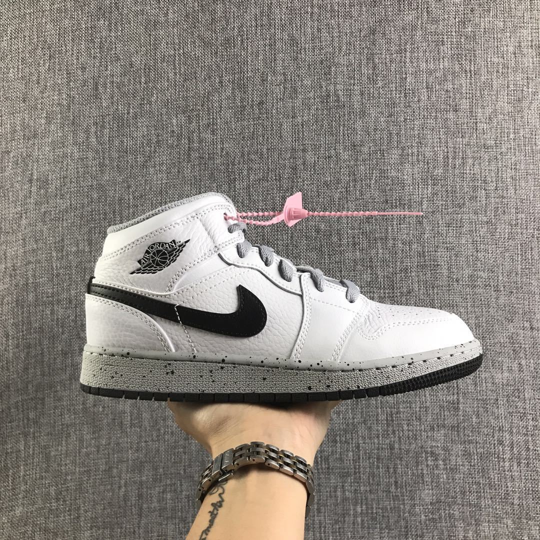 Side view of a white and black Air Jordan 1 Mid GS sneaker with grey laces and a speckled grey midsole.
