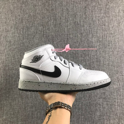 Side view of a white and black Air Jordan 1 Mid GS sneaker with grey laces and a speckled grey midsole.